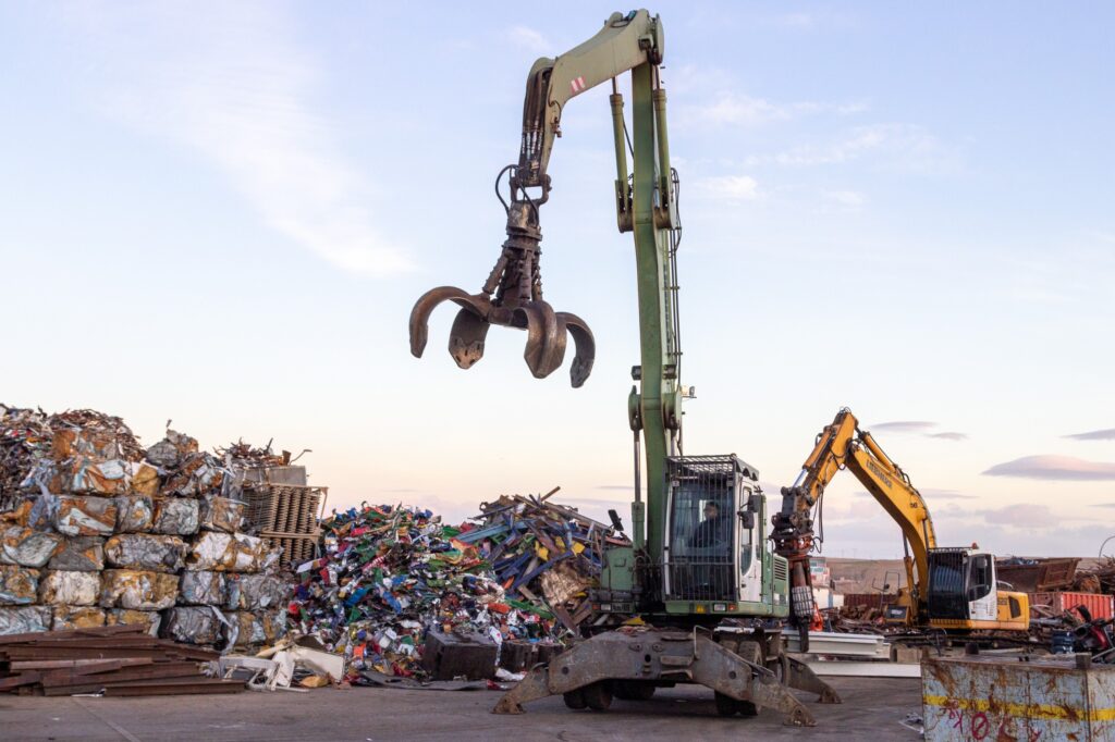 Excavadora industrial trabajando en el reciclaje de metales en la planta de Toferla S.L. en Madrid.